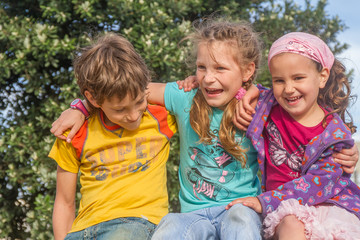 three happy kids - boy and girls - outdoor portrait