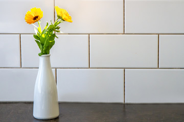 beautiful fresh flowers near kitchen wall of white ceramic tales