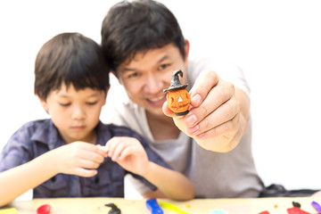 Father is playing Halloween clay with his son over white background