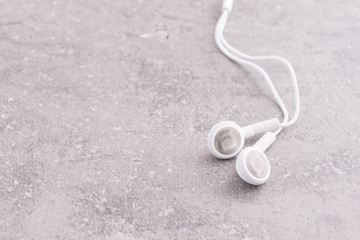 Fototapeta na wymiar White headphones lying on stone table. Concept of audio, sound or mobile accessory.