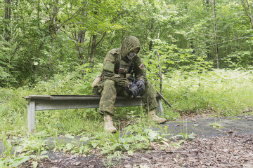 The soldier in field uniform and a mask sitting on a bench