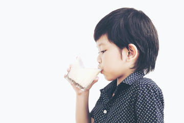 Vintage photo of Asian boy is drinking a glass of milk over white background