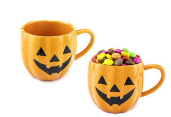 Halloween candies in pumpkin face two cups isolated over white