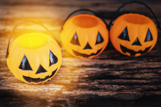 Dark tone photo with warm spotlight of empty Halloween pumpkin face buckets on old wooden texture