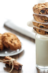 Homemade oatmeal cookies with nuts and raisins and glass of milk on dark wooden background, closeup, selective focus