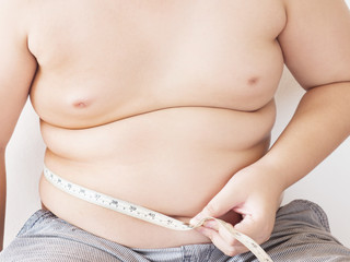A fat boy is measuring his belly using tape meter