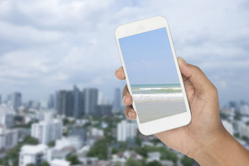 picture of seascape in smartphone with buildings blur background