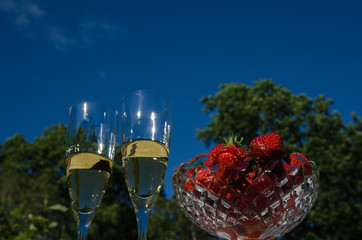 Two glasses champagne and strawberries in a bowl