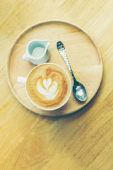 cup of coffee with heart pattern in a white cup on wooden backgr