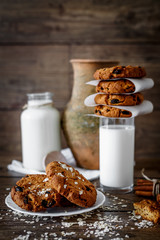 Homemade oatmeal cookies with nuts and raisins and glass of milk on dark wooden background, closeup, selective focus