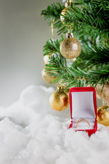 
wedding ring under the Christmas tree decorated with golden balls