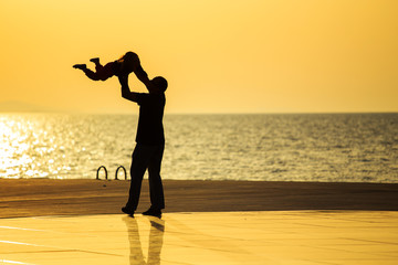 Father and daughter are playing at sunset