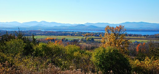Naklejka premium Autumn Panorama of forests lake and mountains in rural setting