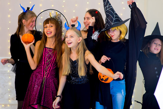 Happy group of teenagers dance in Halloween costumes