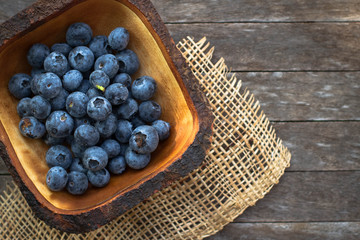 Tasty ripe blueberries with mint in bowl on table close up. Blueberries in a bowl on a wooden table.