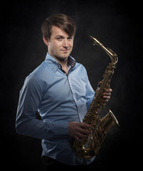 Fototapeta na wymiar Attractive saxophonist on a dark background.