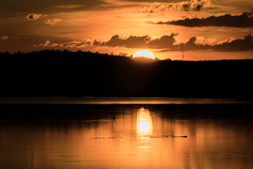 Beautiful orange sky dark clouds at sunset reflection on the lake water with silluette of mountain - Half of a Yellow Sun
