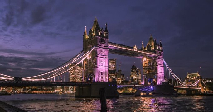 Time lipse panning view of tower bridge floodlit at night with the City of London in the background