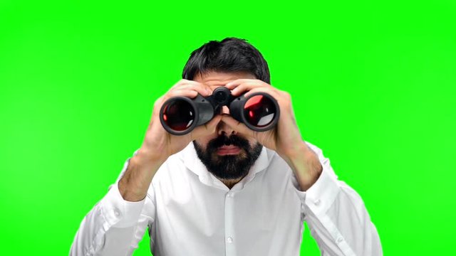 Handsome man with binoculars on green screen chroma key