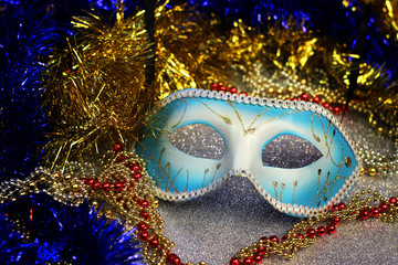 Brilliant blue carnival mask close up on shiny background with festive colored garlands