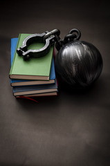 Student debt concept with a stack of books next to a ball and chain symbolizing the burden tuition...