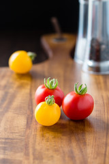 4 rote und gelbe Cocktailtomaten auf Hozlbrett gruppiert