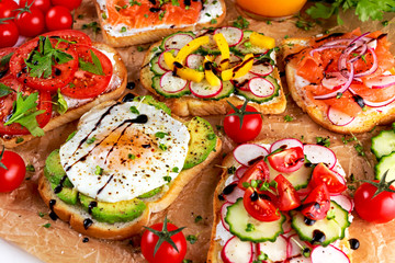 Variety of vegetarian toast sandwiches with salmon, raddish, tomatoes, cucumber, avocado,fried egg and sweet pepper