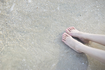 woman legs laying at the sand beach.Feet of a young woman on a beach.sunbathing