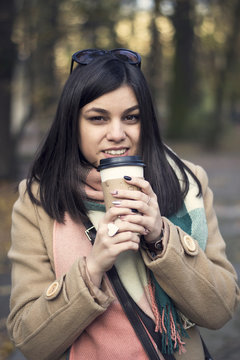 Young beautiful girl with coffee in a paper cup.