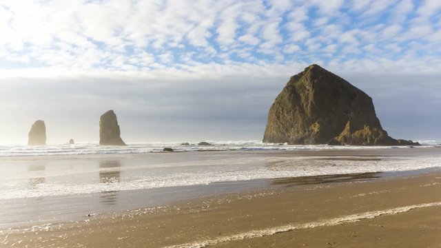 Ultra high definition 4k time lapse movie of clouds and sky over famous Haystack Rock with water reflection at low tide along Pacific Ocean in Cannon Beach Oregon 4096x2304 uhd