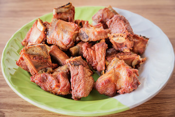 Fried pork on a plate placed on a wooden table.