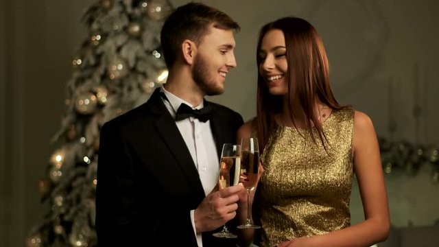 Beautiful loving couple holding glasses of champagne and celebrating Happy New Year day.