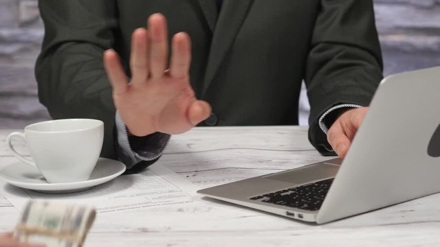 Man offering bribe money to a businessman and gets refused by a hand gesture.