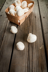 Raw mushrooms champignon in a basket on a rustic wooden table, copy space