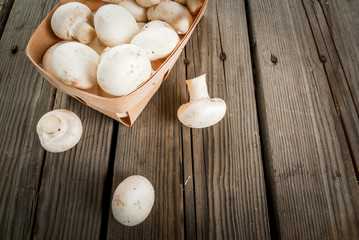 Raw mushrooms champignon in a basket on a rustic wooden table, copy space