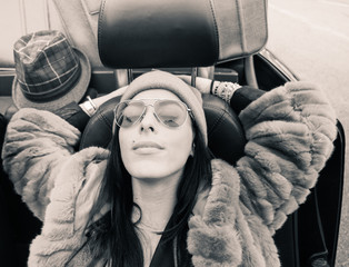 Fashion portrait of young woman relaxing in cabriolet roadster car