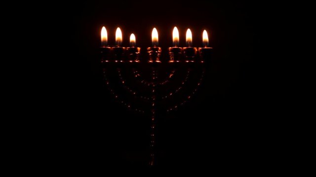Golden Menorah with seven pin shines in the darkness