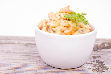 Risotto with chicken, bell pepper, onion, portobello and parsley on a wooden background