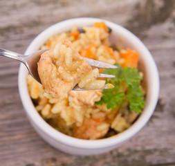 Risotto with chicken, bell pepper, onion, portobello and parsley on a wooden background