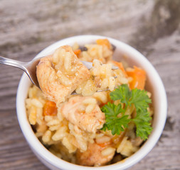 Risotto with chicken, bell pepper, onion, portobello and parsley on a wooden background