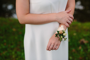 wedding decoration for the bride's hand . white flowers with ribbons on the bracelet . female hands closeup