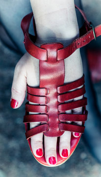 Female hand stuffed in sandals red. The nails are painted with red lacquer.
