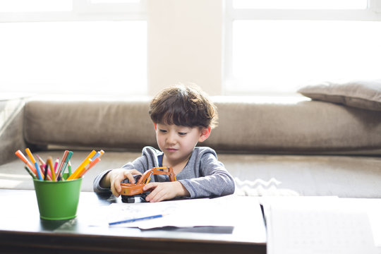 Little boy playing with a toy when doing homework