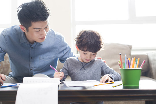Father helping son while doing homework
