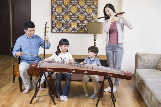 Young family playing traditional musical instruments at home