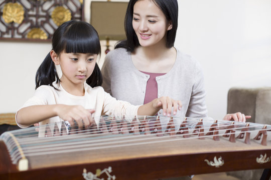 Mother teaching traditional musical instrument zither