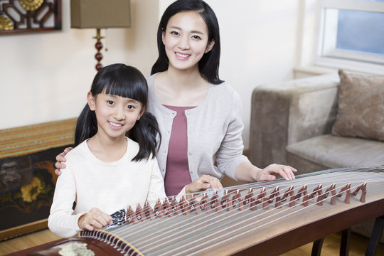 Mother teaching traditional musical instrument zither
