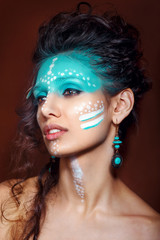 attractive young woman in ethnic jewelry . close up portrait. Beautiful girl shaman. Portrait of a woman with a painted face. Creative makeup and bright style.