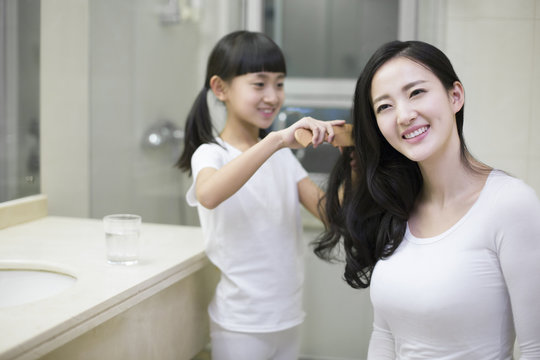 Little girl combing mom's hair