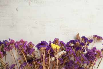 Dry statices flowers on the white wooden table, top view, selective focus; copy space for the text